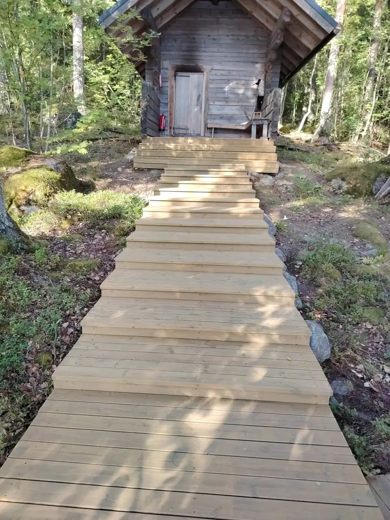 Uudet puuportaat ja polku metsässä olevalle hirsisaunalle
